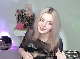 Hot blonde girl playing on ukulele and singing in naughty outfit